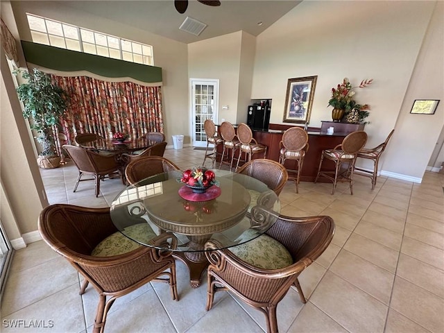 dining area featuring a towering ceiling and light tile patterned floors