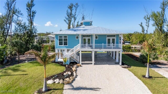 coastal inspired home featuring french doors, a front lawn, and a carport