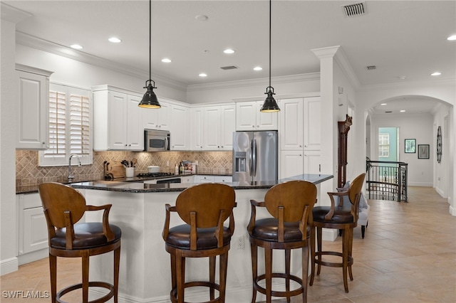 kitchen with white cabinetry, dark stone counters, hanging light fixtures, a center island, and stainless steel appliances