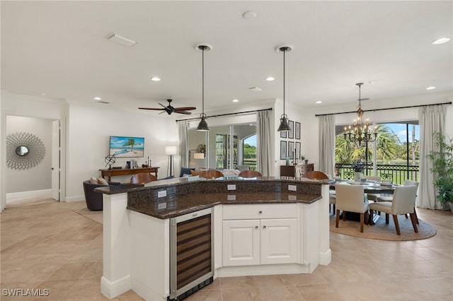 kitchen featuring wine cooler, decorative light fixtures, a kitchen island, dark stone counters, and white cabinets