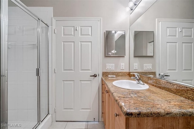 bathroom with tile patterned flooring, vanity, and a shower with door