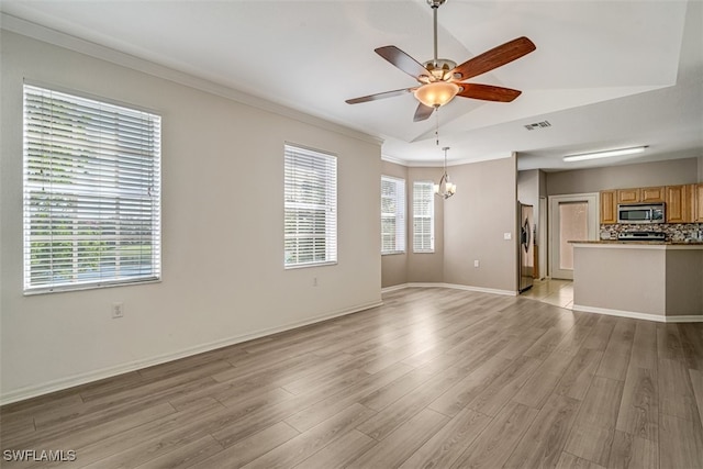 unfurnished living room featuring ceiling fan with notable chandelier, light hardwood / wood-style floors, lofted ceiling, and crown molding