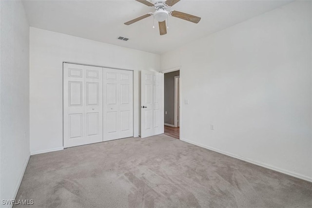 unfurnished bedroom featuring light carpet, a closet, and ceiling fan