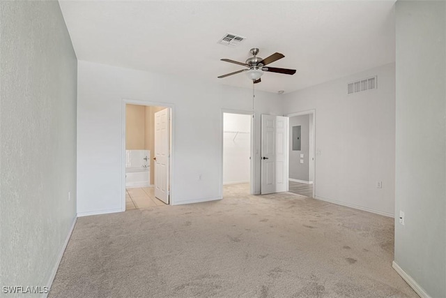 unfurnished bedroom with a walk in closet, ensuite bath, ceiling fan, electric panel, and a closet