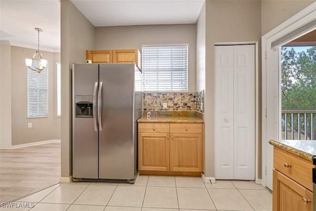 kitchen with hanging light fixtures, tasteful backsplash, stainless steel refrigerator with ice dispenser, a chandelier, and light tile patterned floors