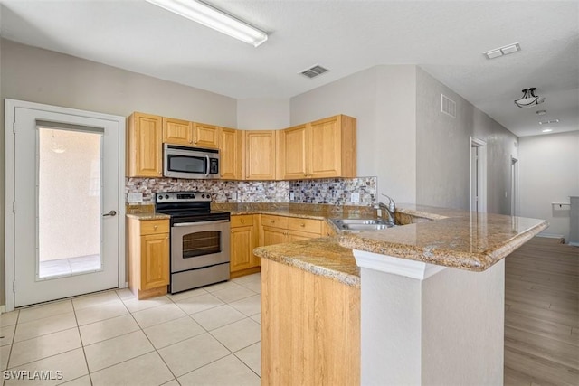 kitchen with kitchen peninsula, sink, light stone counters, appliances with stainless steel finishes, and light brown cabinetry