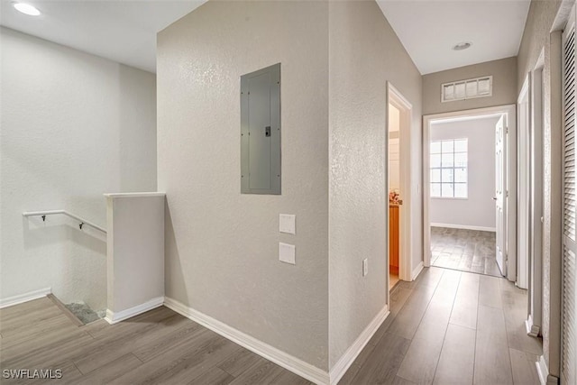 hallway featuring electric panel and hardwood / wood-style flooring