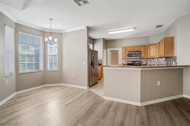 kitchen featuring backsplash, kitchen peninsula, a chandelier, light hardwood / wood-style floors, and appliances with stainless steel finishes