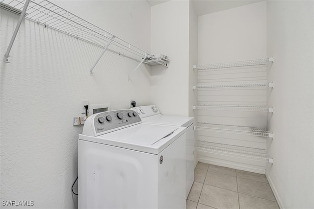 laundry area with washer and clothes dryer and light tile patterned floors