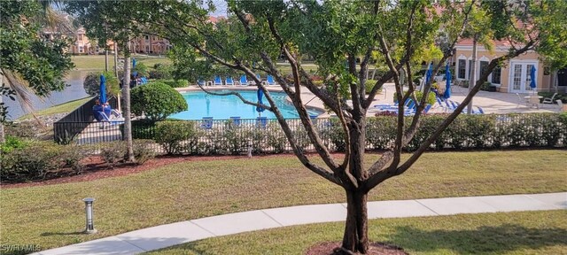 view of property's community with a pool and a lawn