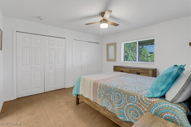 tiled bedroom featuring ceiling fan and multiple closets