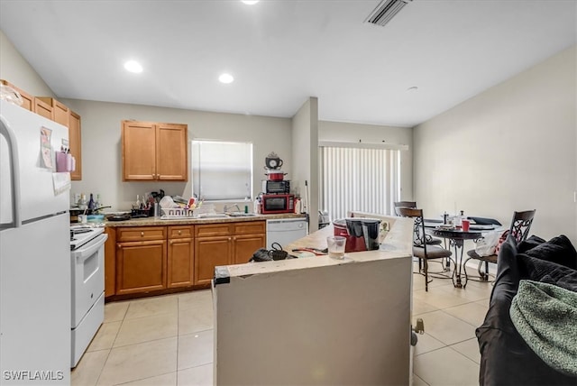 kitchen featuring a kitchen island, white appliances, sink, and light tile patterned flooring