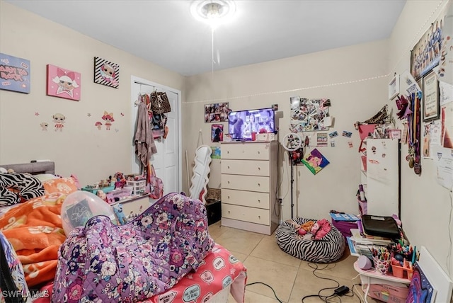 bedroom with a closet, white fridge, and light tile patterned flooring