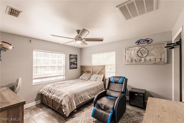 bedroom featuring a ceiling fan, wood finished floors, visible vents, and baseboards