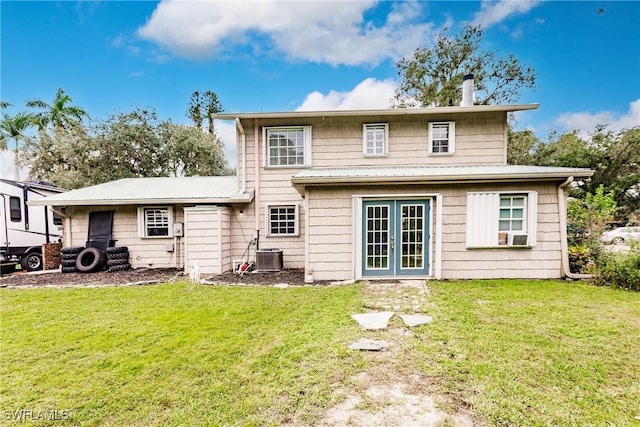 back of house featuring central AC unit and a lawn