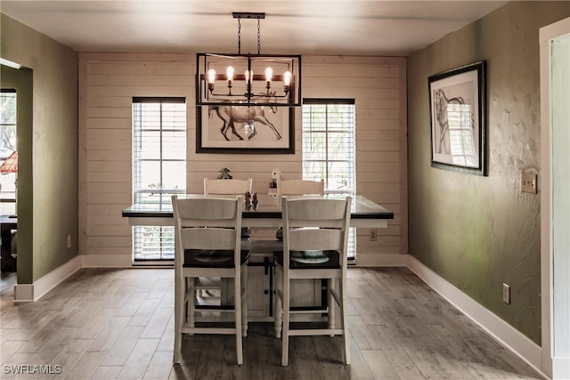 dining space featuring wood walls, a chandelier, and wood-type flooring