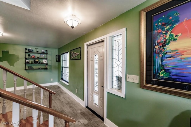 foyer entrance featuring stairs, wood finished floors, and baseboards