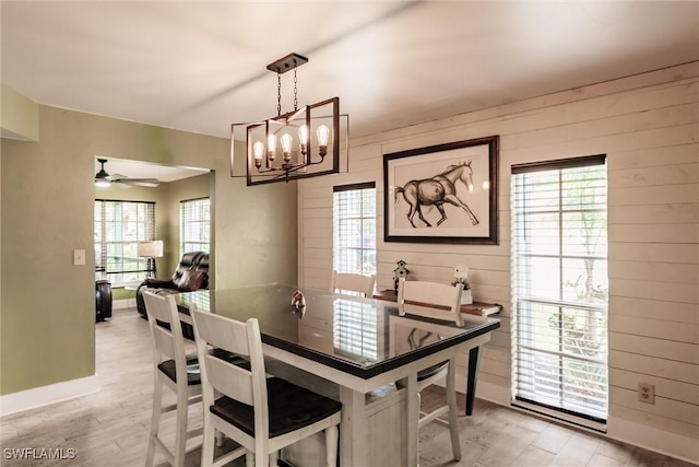dining area featuring wood walls, plenty of natural light, light wood-style flooring, and baseboards