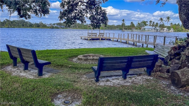 dock area with a lawn, an outdoor fire pit, and a water view