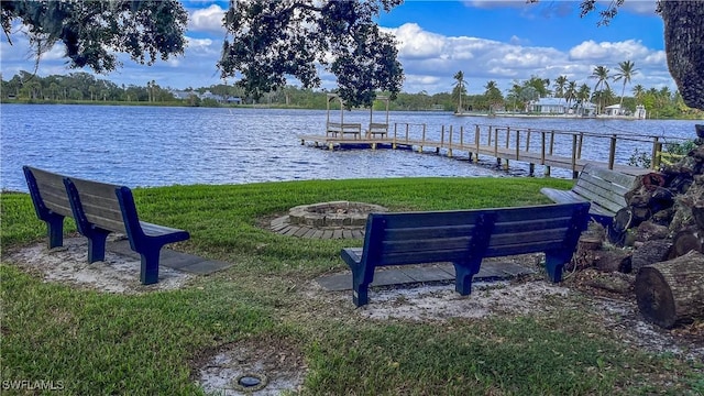 view of dock with an outdoor fire pit, a water view, and a lawn