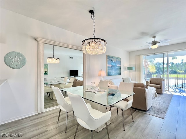 dining room with light wood-type flooring and ceiling fan with notable chandelier