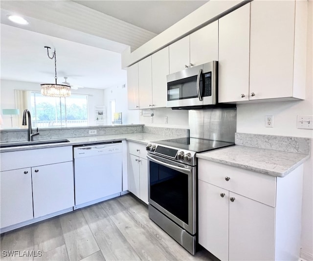 kitchen with stainless steel appliances, light wood-type flooring, white cabinetry, pendant lighting, and sink