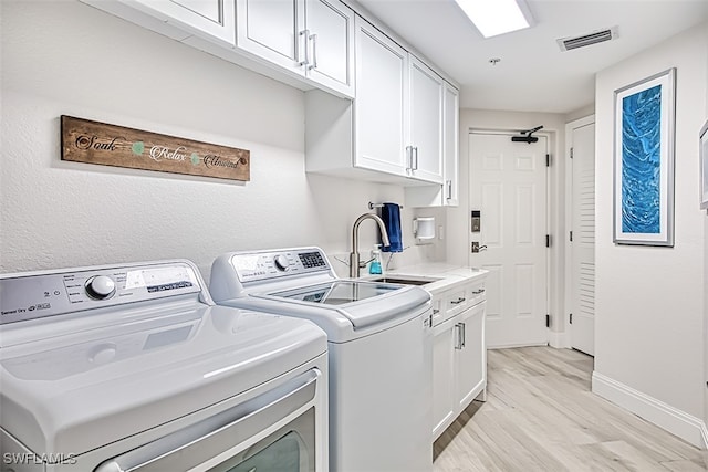 washroom featuring sink, light wood-type flooring, cabinets, and independent washer and dryer