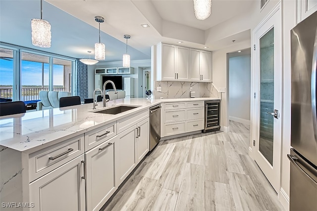 kitchen with stainless steel appliances, beverage cooler, white cabinets, kitchen peninsula, and sink