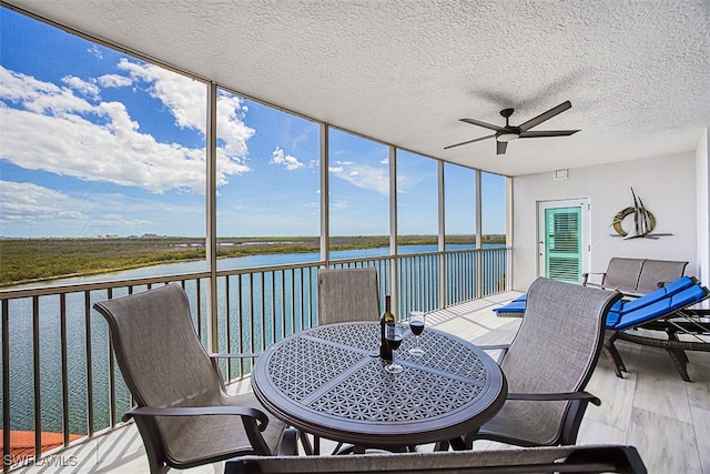 sunroom / solarium with a water view and ceiling fan