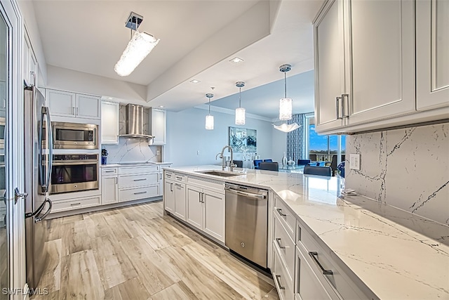 kitchen with sink, tasteful backsplash, wall chimney range hood, white cabinetry, and appliances with stainless steel finishes