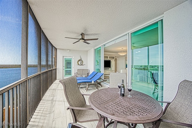 sunroom featuring a water view and ceiling fan