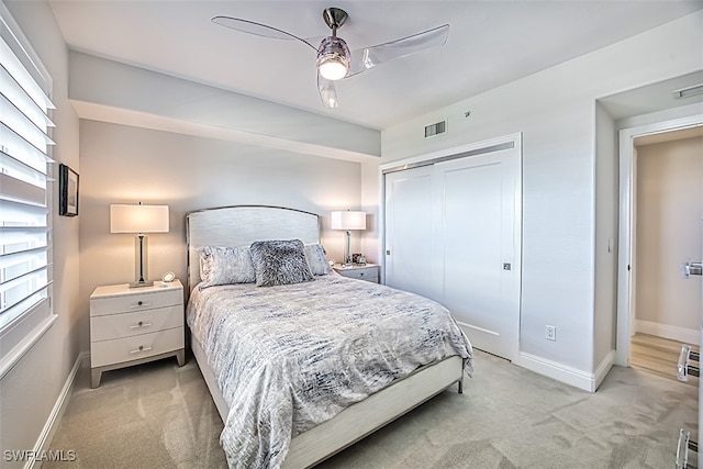 bedroom featuring a closet, light colored carpet, and ceiling fan