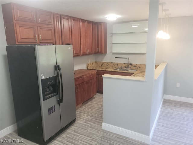 kitchen featuring pendant lighting, sink, stainless steel refrigerator with ice dispenser, and light hardwood / wood-style flooring