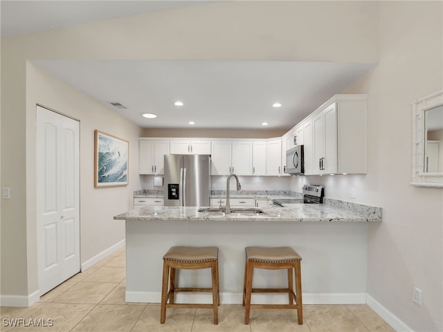 kitchen with light stone counters, sink, white cabinetry, and stainless steel appliances