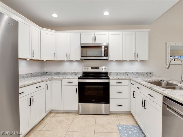 kitchen featuring light stone countertops, appliances with stainless steel finishes, sink, light tile patterned floors, and white cabinets