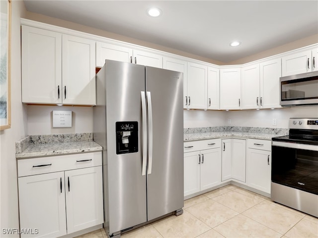 kitchen with light stone counters, white cabinets, light tile patterned floors, and appliances with stainless steel finishes