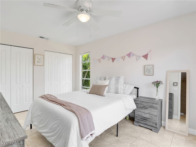 bedroom with ceiling fan, light tile patterned flooring, and two closets