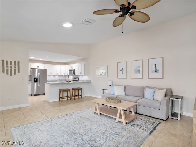 tiled living room with ceiling fan, sink, and vaulted ceiling