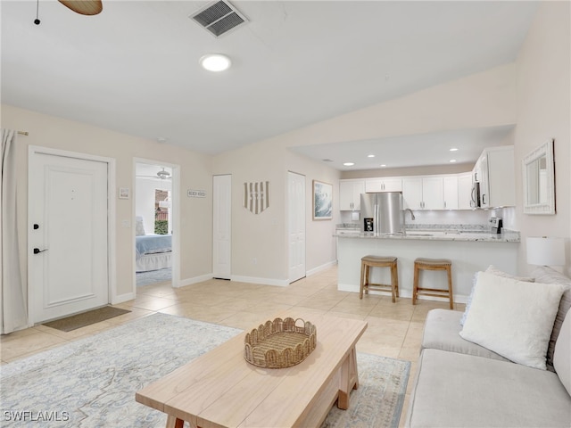 living room with ceiling fan, sink, light tile patterned floors, and lofted ceiling