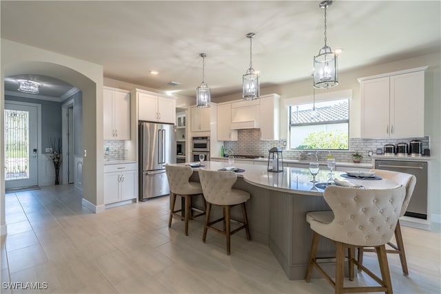 kitchen featuring tasteful backsplash, white cabinetry, a center island with sink, and stainless steel appliances