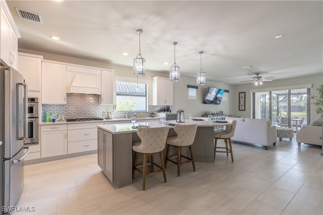 kitchen with white cabinets, decorative light fixtures, and a kitchen island with sink