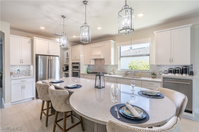 kitchen with tasteful backsplash, white cabinetry, a center island, and pendant lighting