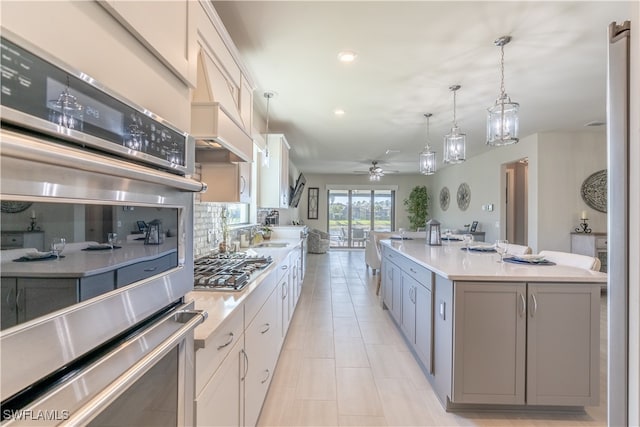 kitchen featuring white cabinetry, a center island with sink, ceiling fan, and appliances with stainless steel finishes