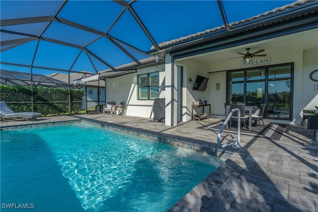 view of swimming pool with a patio area, ceiling fan, and glass enclosure