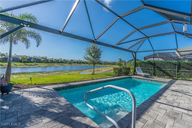 view of pool featuring glass enclosure, a water view, and a patio