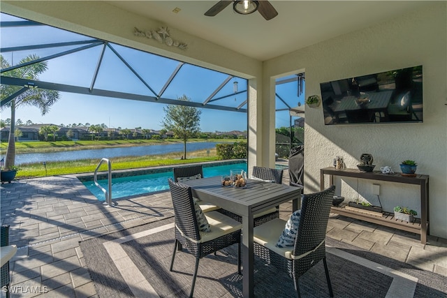 view of pool with a lanai, ceiling fan, a water view, and a patio