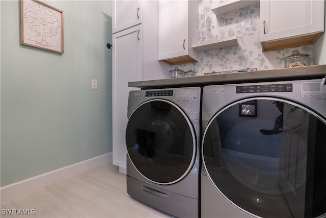 clothes washing area featuring cabinets and separate washer and dryer