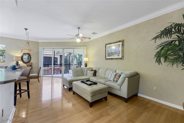 living room featuring light hardwood / wood-style floors, ceiling fan, and crown molding