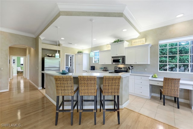 kitchen featuring appliances with stainless steel finishes, a spacious island, light hardwood / wood-style flooring, white cabinetry, and a breakfast bar area