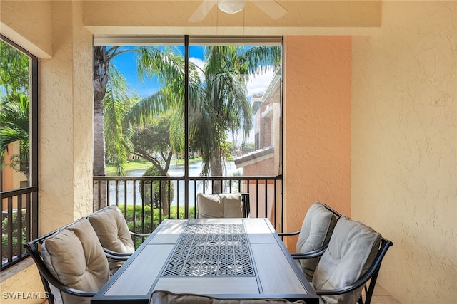 sunroom / solarium with a water view, ceiling fan, and a healthy amount of sunlight